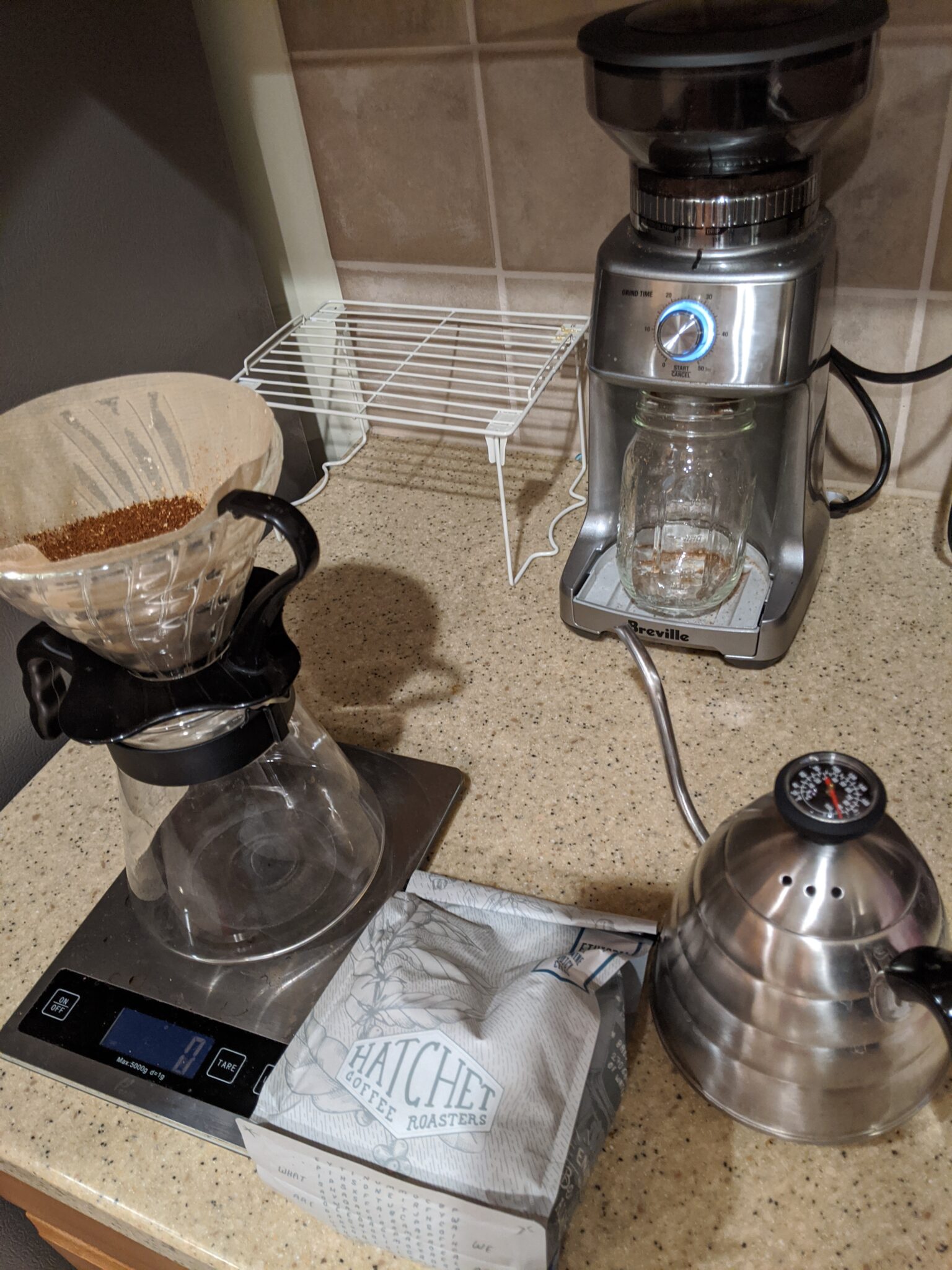 Coffee grinder, scale, kettle, and pour over device on counter.